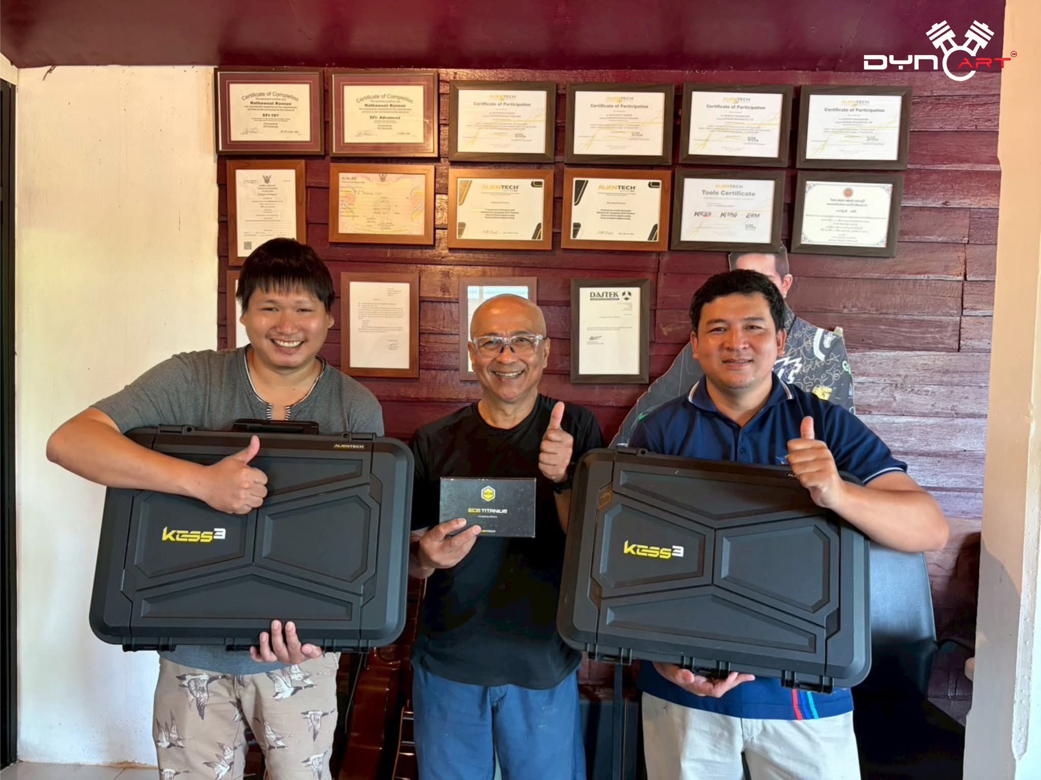 ทีม DynoArt กับเครื่องมือ Alientech KESS3 หน้ากำแพงใบรับรอง